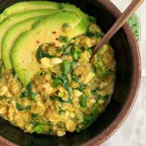 savory oatmeal with spinach and avocado in a bowl with a spoon.