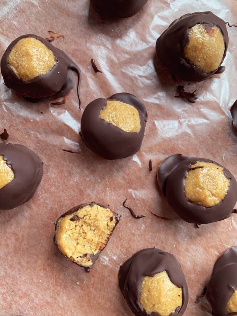 chocolate covered peanut butter buckeyes on a brown cutting board and wax paper