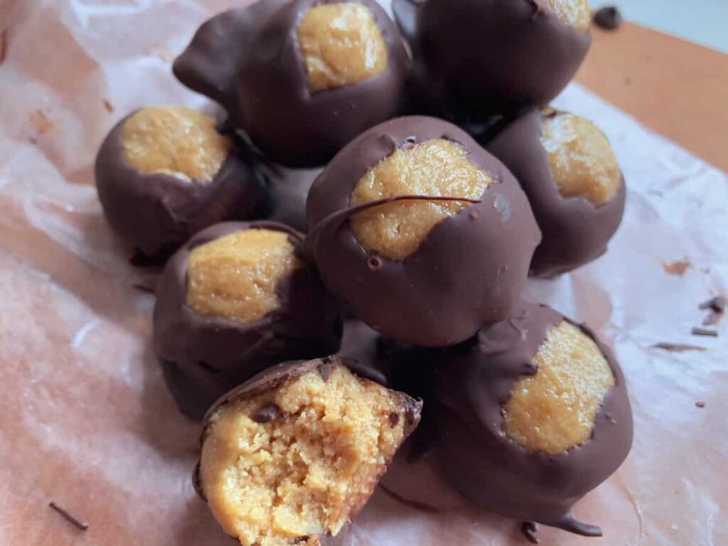 healthy vegan peanut butter buckeyes with chocolate on a parchment paper and a brown surface
