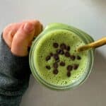 green shamrock shake in a mason jar topped with mini chocolate chips held in hand