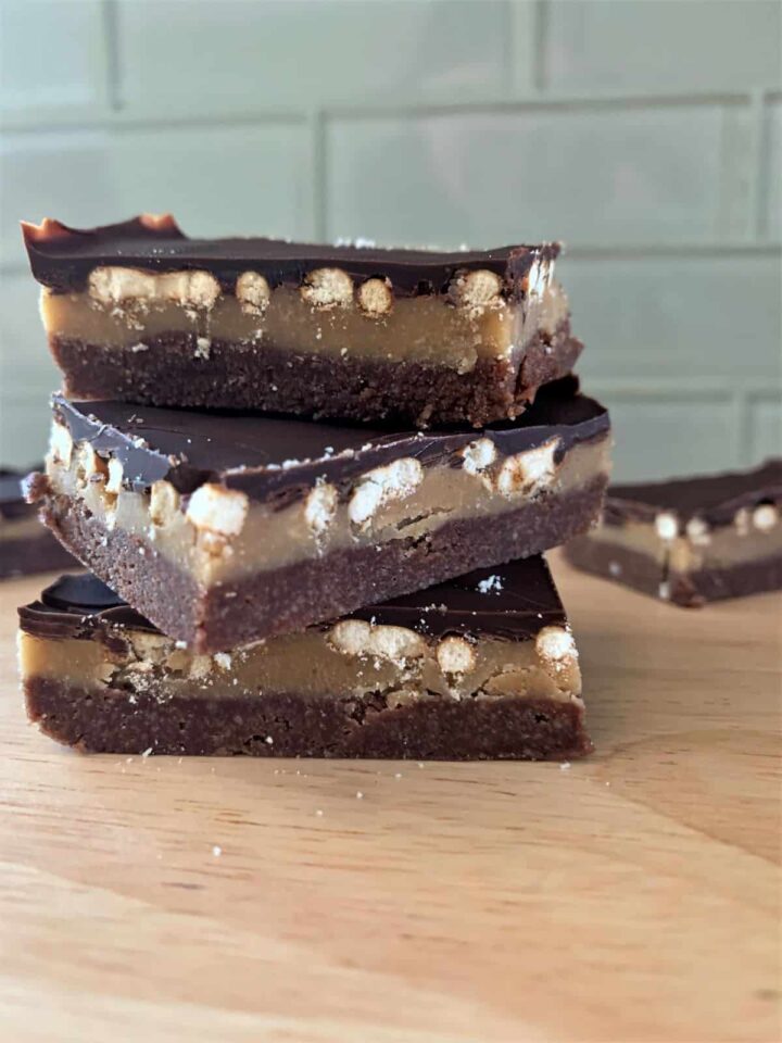 chocolate pretzel millionaire bars stacked three high on a cutting board