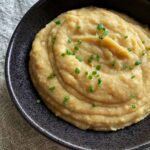 celery root puree with green onions in a black bowl