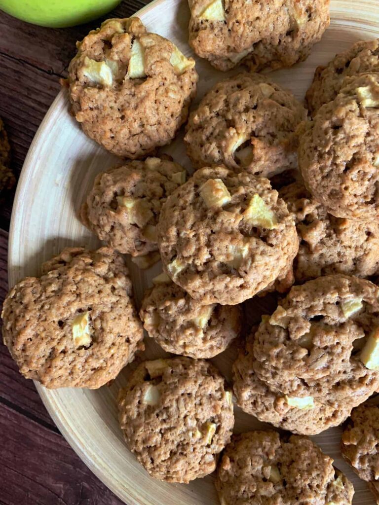 apple cider cookies on a bamboo plate with green apple