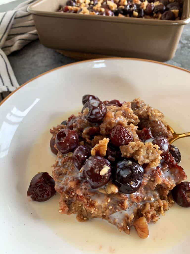 cherry quinoa breakfast bake on a white plate with milk poured over top