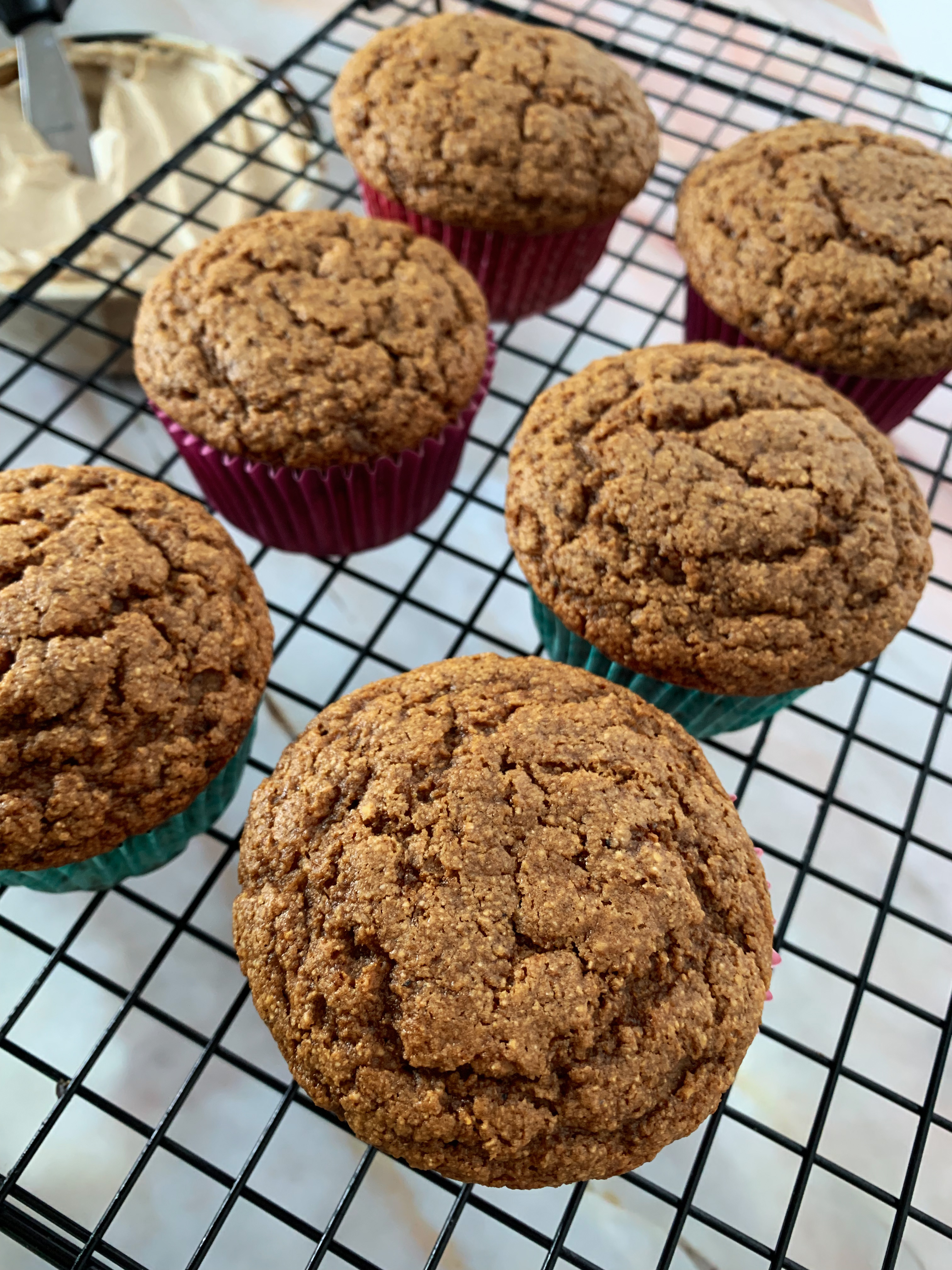 vanilla oat cupcakes on a black wire cooling rack