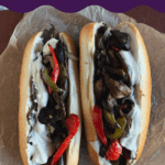 Vegan philly cheesesteak with oyster mushrooms, peppers, onions and melted cheese on a long roll on parchment paper