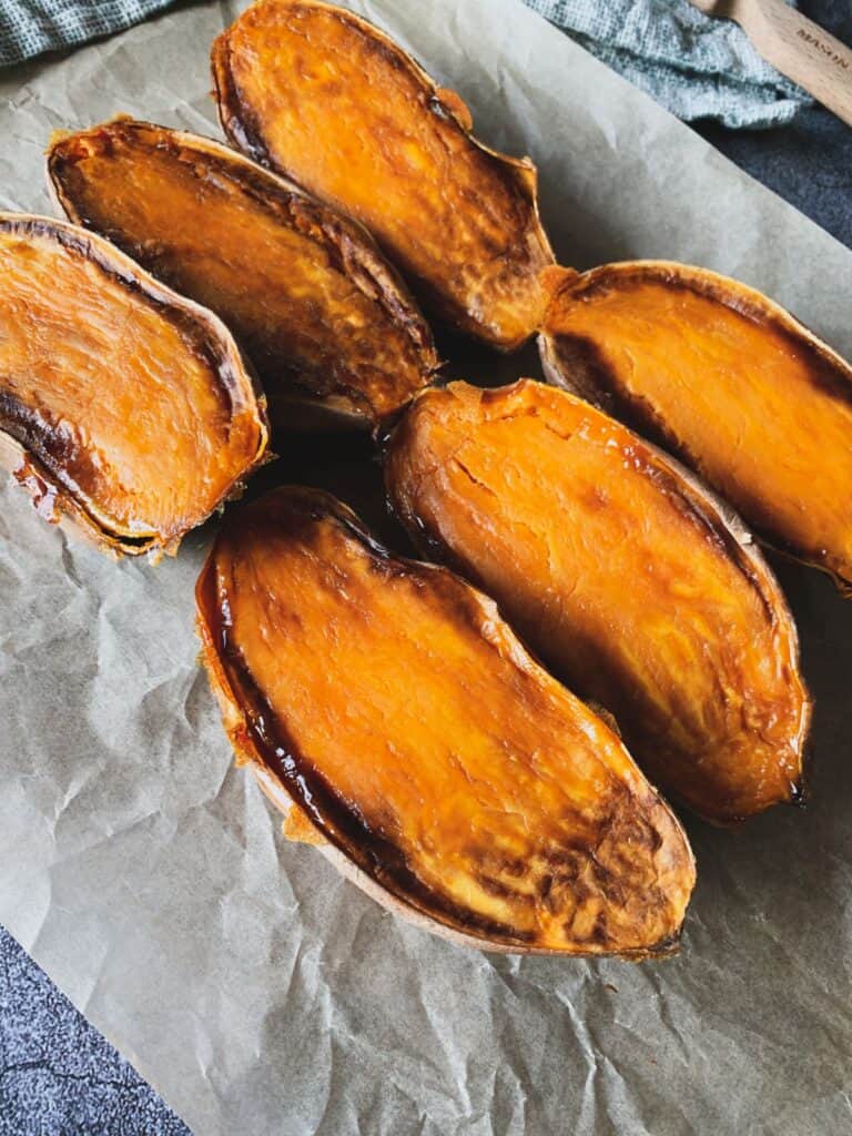 Roasted sweet potatoes with caramelized edges on parchment paper