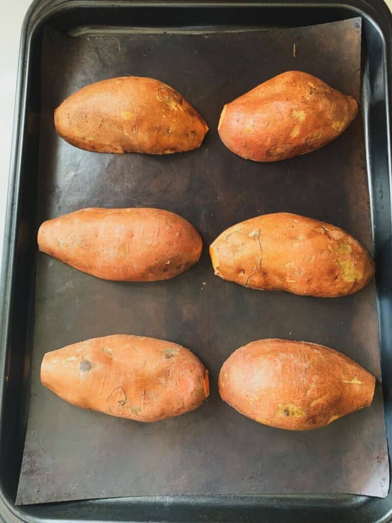 cut raw sweet potatoes lined on a baking sheet ready to roast