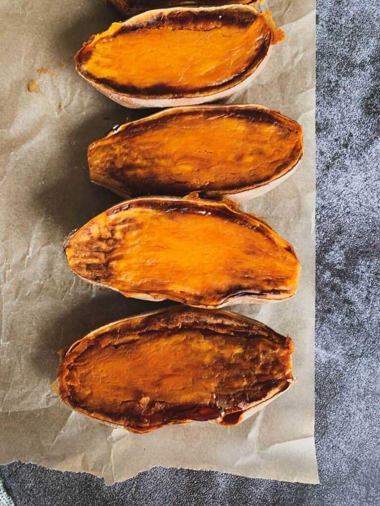 Roasted sweet potatoes cooling on a sheet of parchment paper