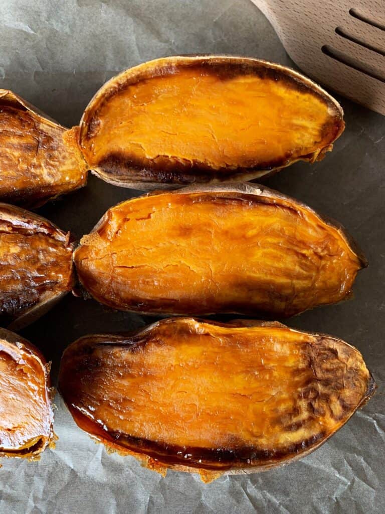 Caramelized roasted sweet potatoes halved on a sheet of parchment