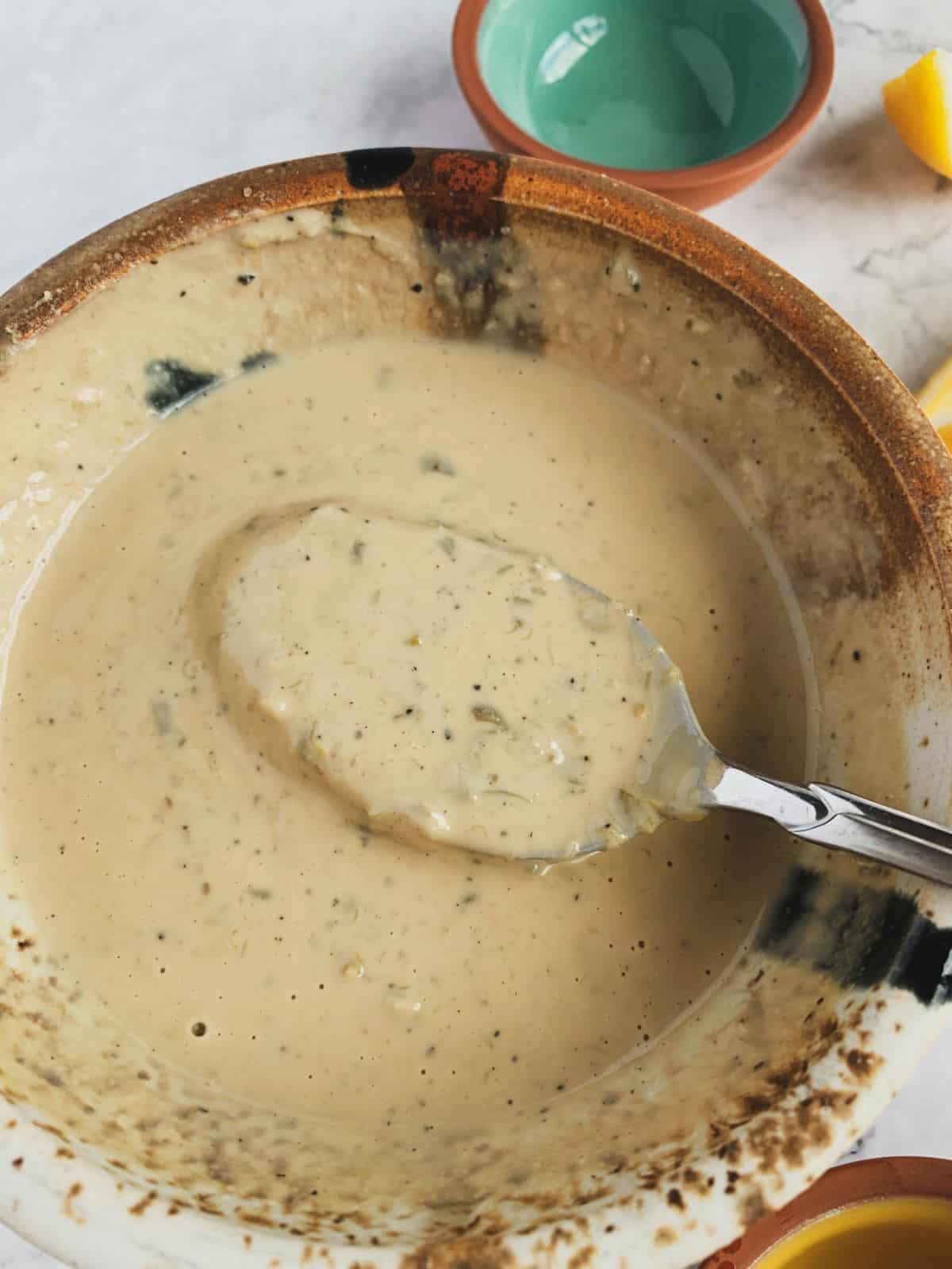 prepared vegan caesar dressing in a ceramic bowl with a spoon