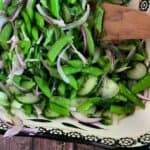 sugar snap pea salad close up image in a white and black bowl