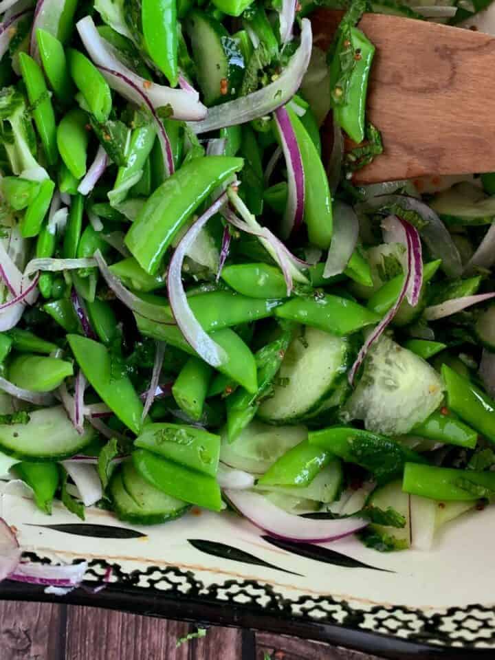 sugar snap pea salad close up image in a white and black bowl