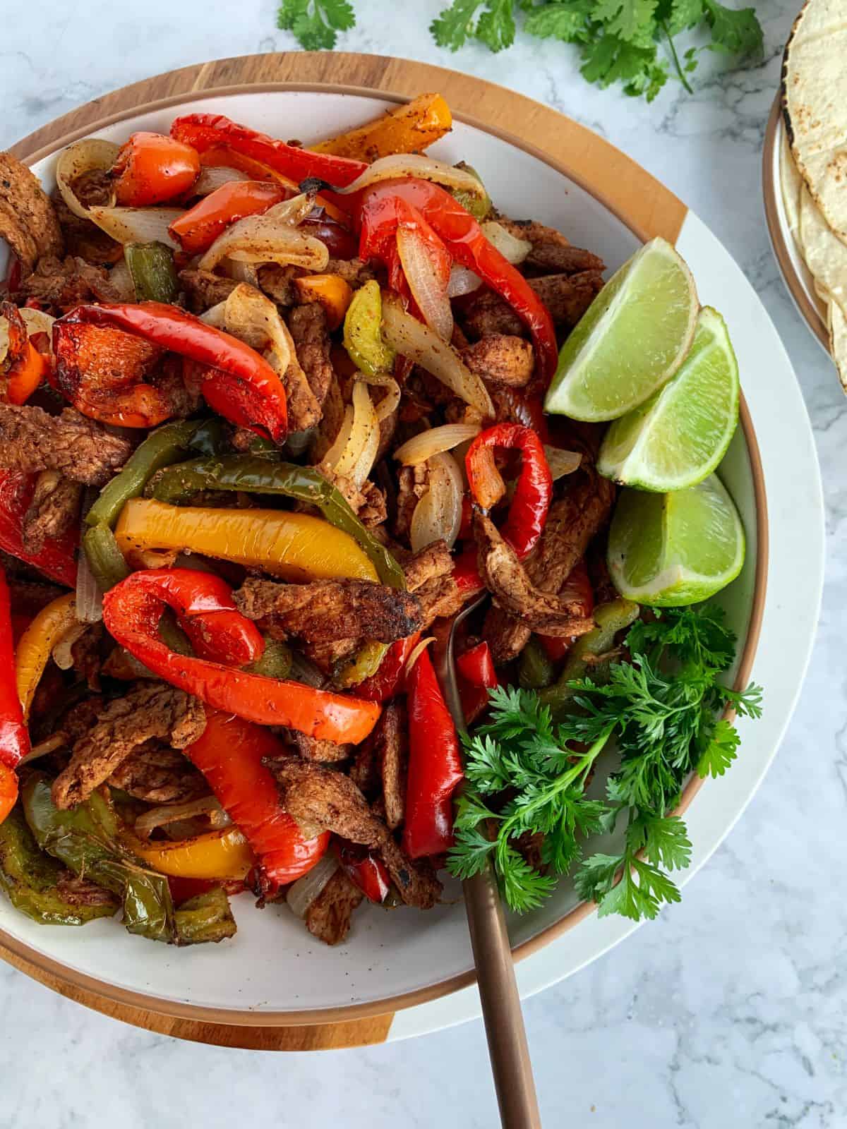 soy curl fajitas made in the air fryer in a white bowl with lime and cilantro