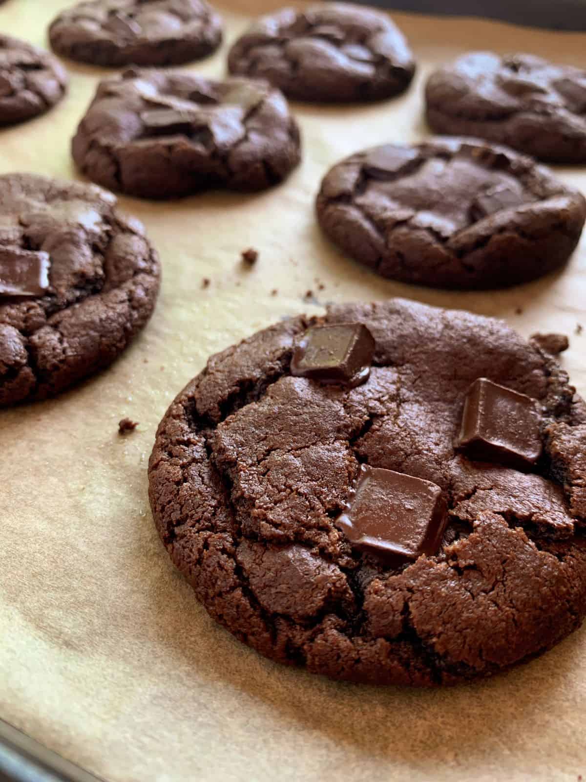 Close view of eggless chocolate cookies on a parchment paper lined baking sheet.