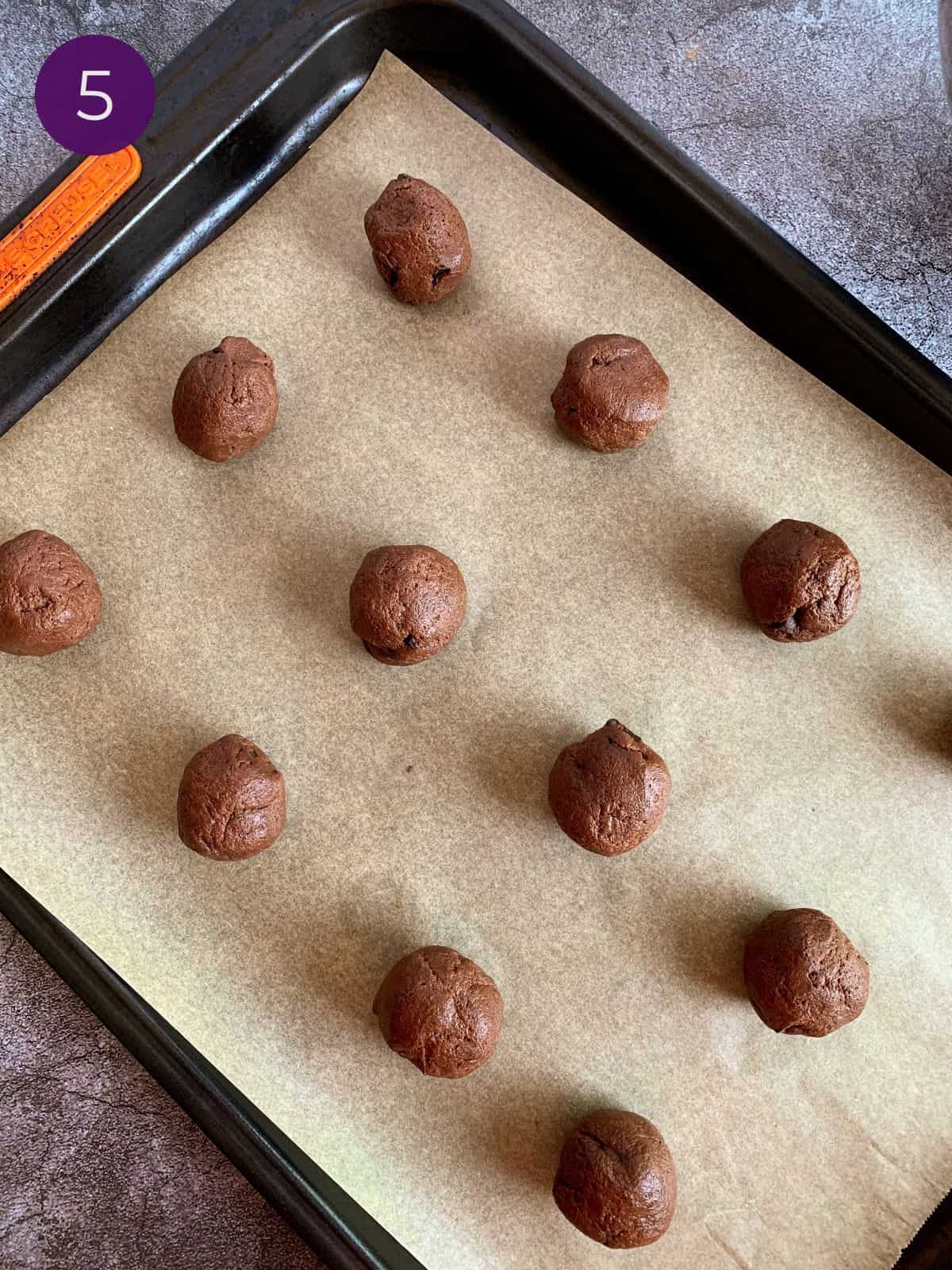 Rolled cookie dough balls prepared and spaced evenly on parchment lined cookie sheet.