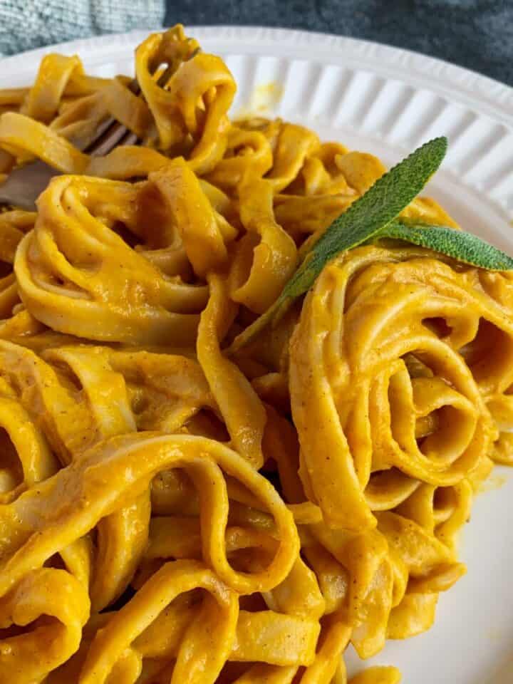 dairy free pumpkin pasta on a white plate with a fork