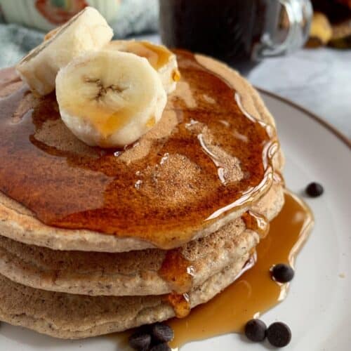 Vegan, blender banana oat pancakes topped with syrup and banana.