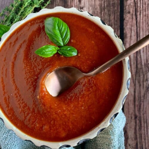 Red pepper tomato sauce in a bowl with a gold spoon.
