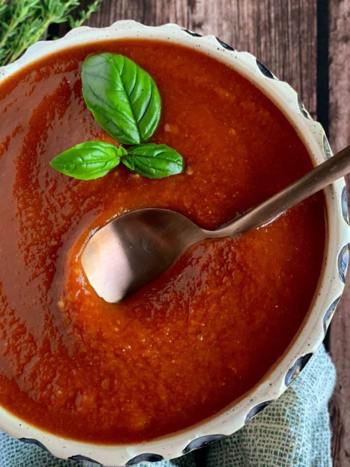 Red pepper tomato sauce in a bowl with a gold spoon.