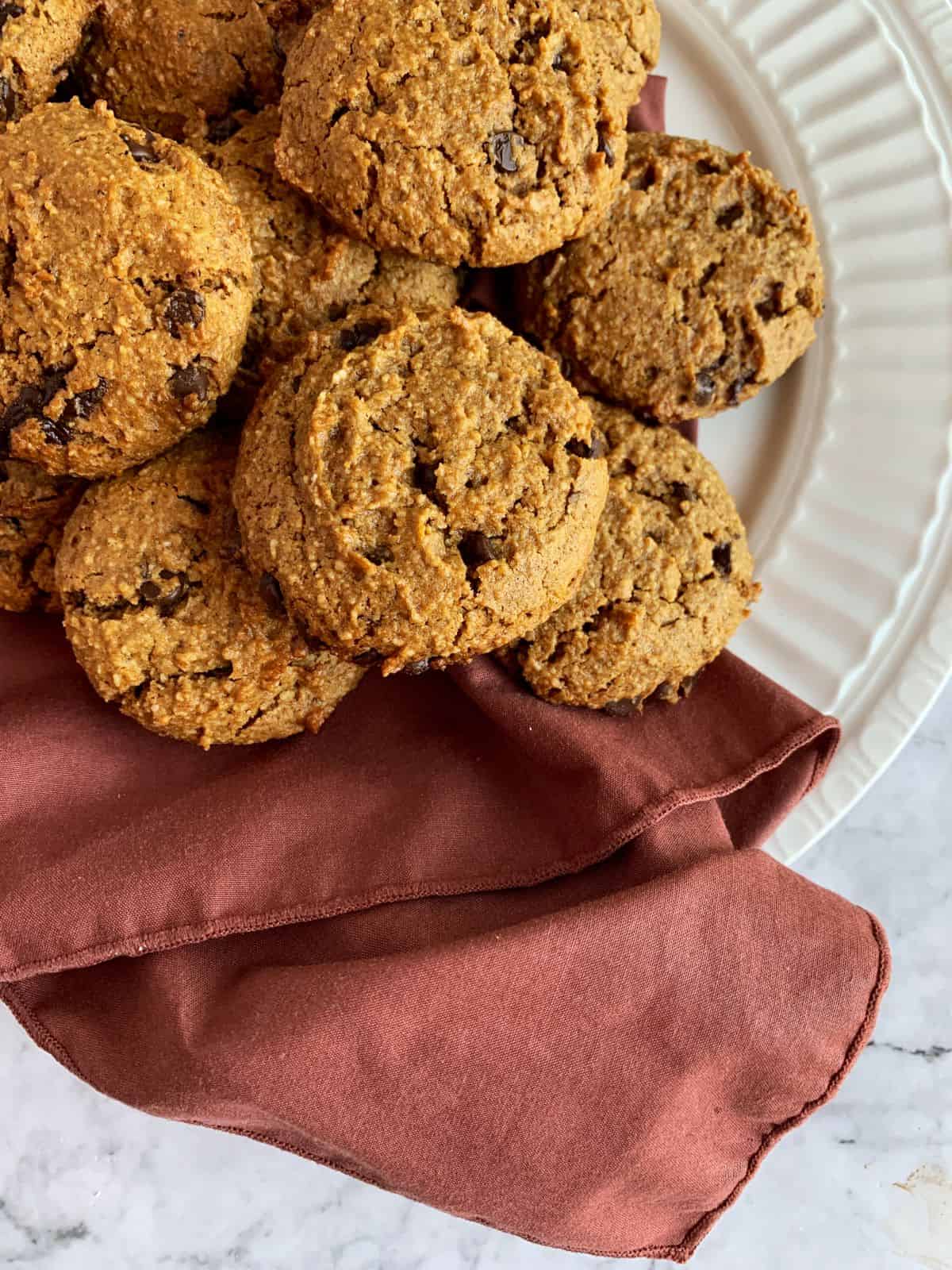 pumpkin spice chocolate chip cookies on a white plate with a cloth napkin.