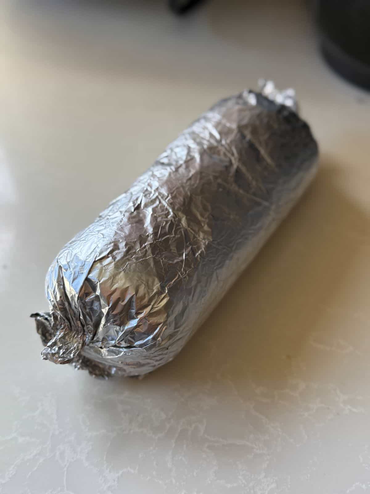 Vegan lunch meat wrapped tightly in parchment and foil before steaming.
